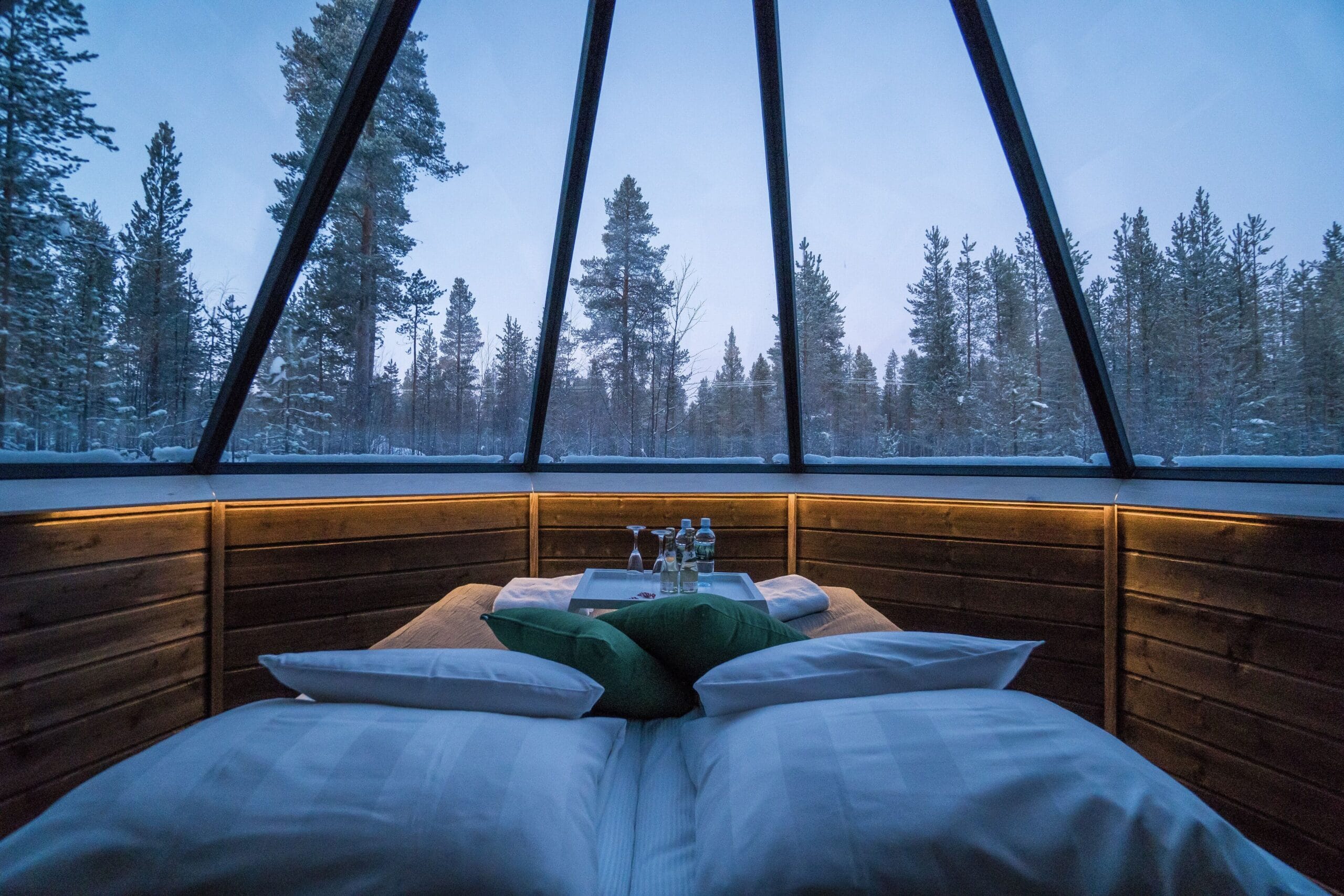 Cozy glass igloo cabin interior with bed under the glass roof at Aurora Village Ivalo, Finland