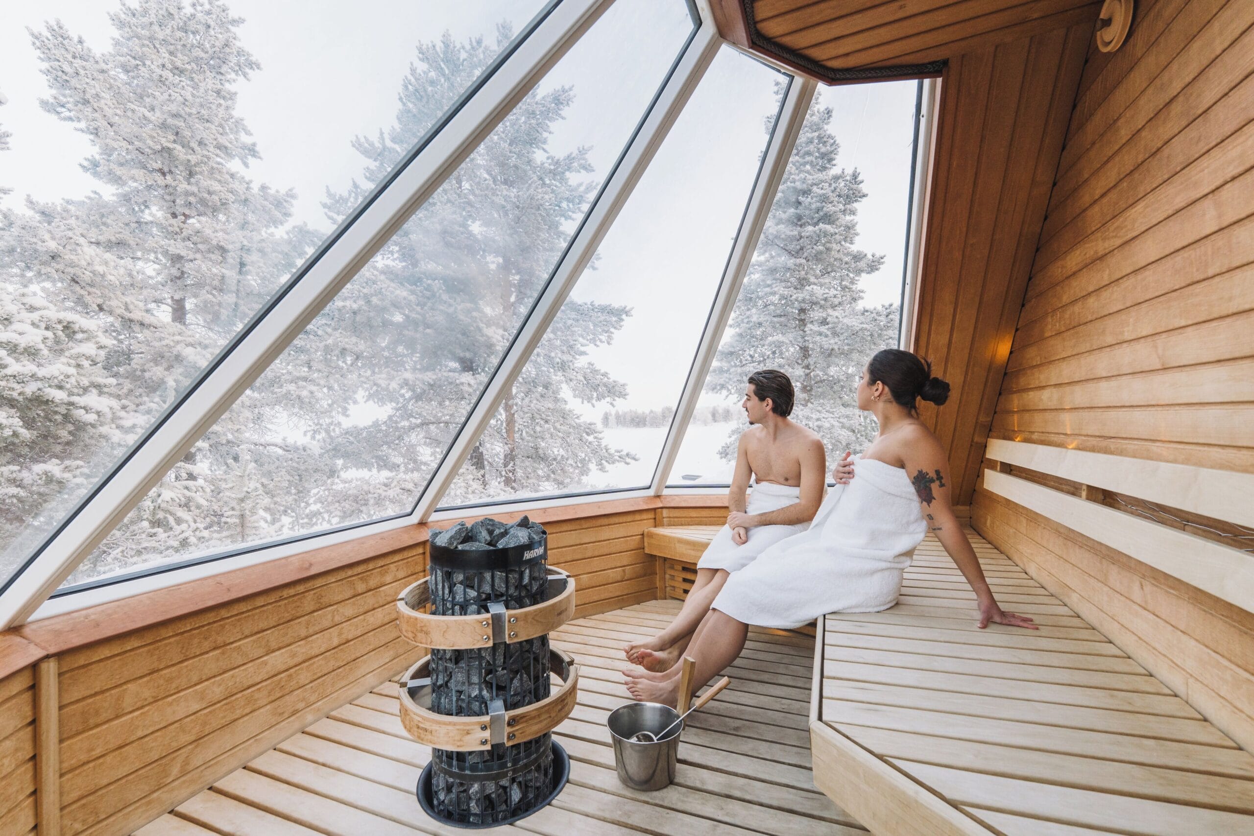 Aurora Cabin interior with bed under a heated thermal glass roof at Wilderness Hotel Inari, Finnish Lapland