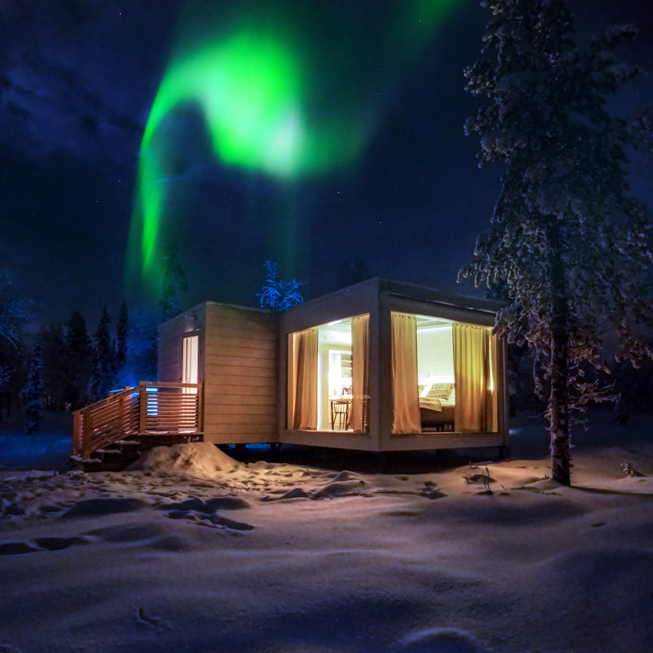 Private outdoor hot tub beside a glass cabin for aurora viewing at Northern Lights Ranch near Levi, Finland
