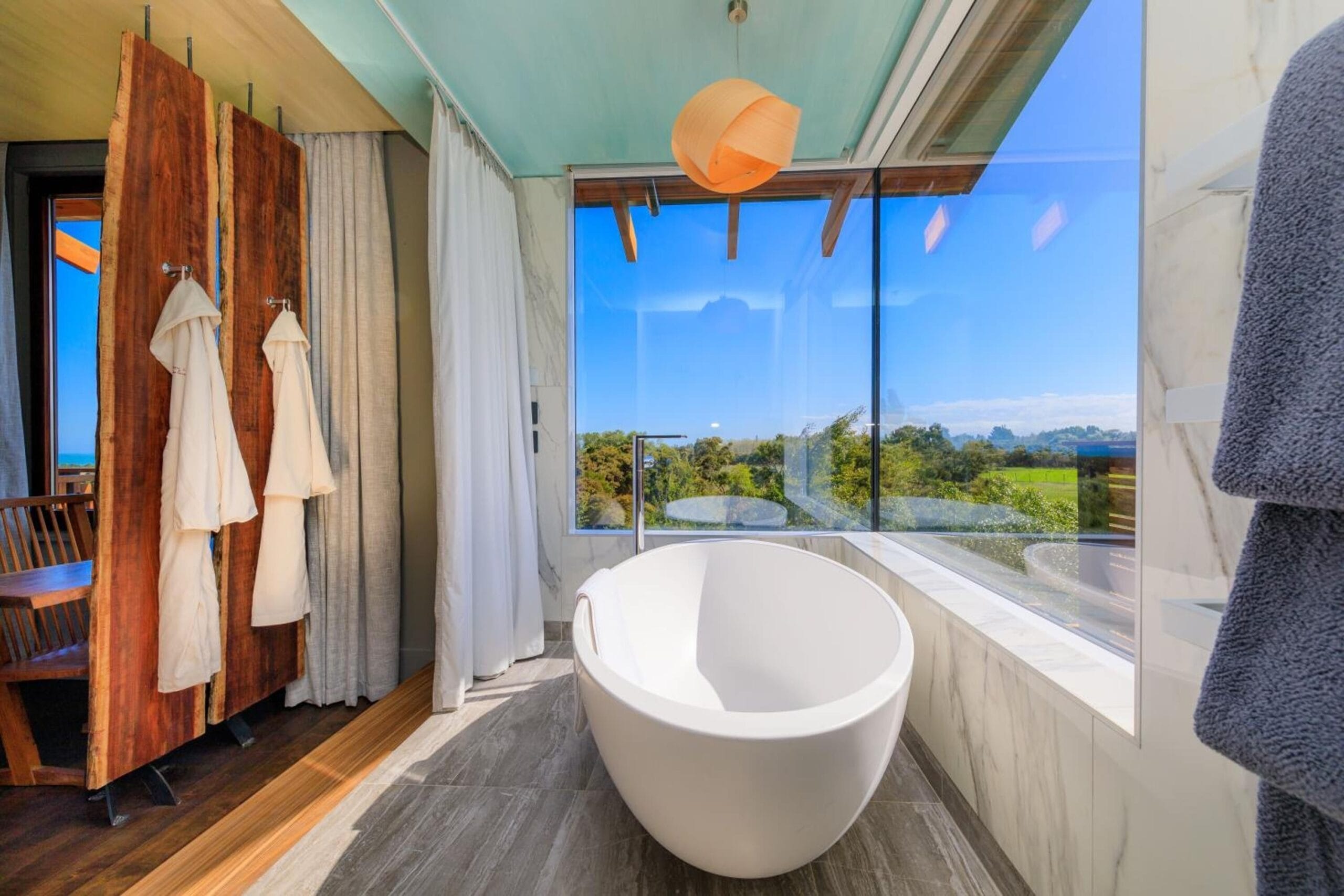 Luxury treehouse interior with fireplace and floor-to-ceiling windows at Hapuku Lodge Tree Houses, New Zealand