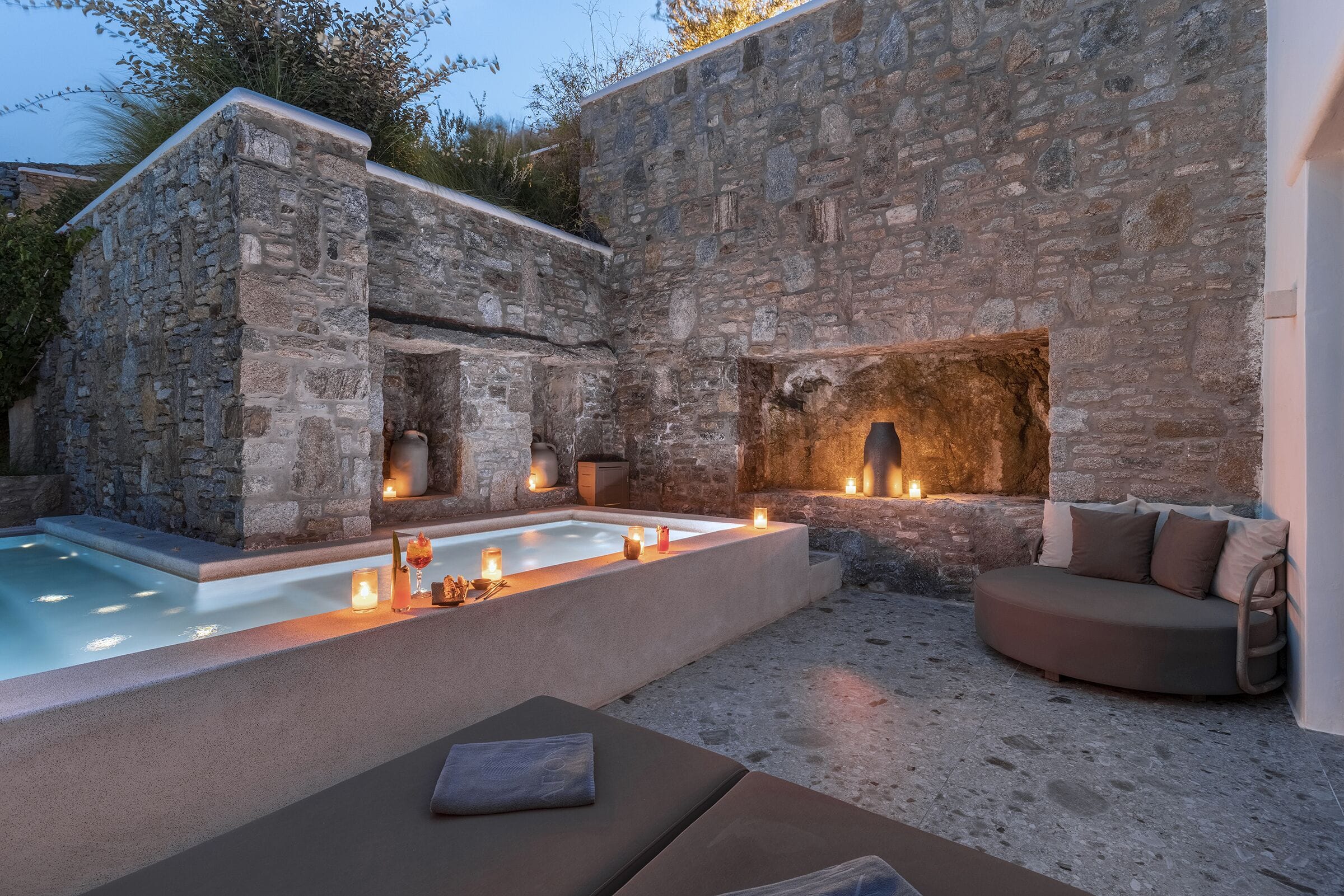 Private pool courtyard framed by stone and oak at Aeonic Suites and Spa in Mykonos