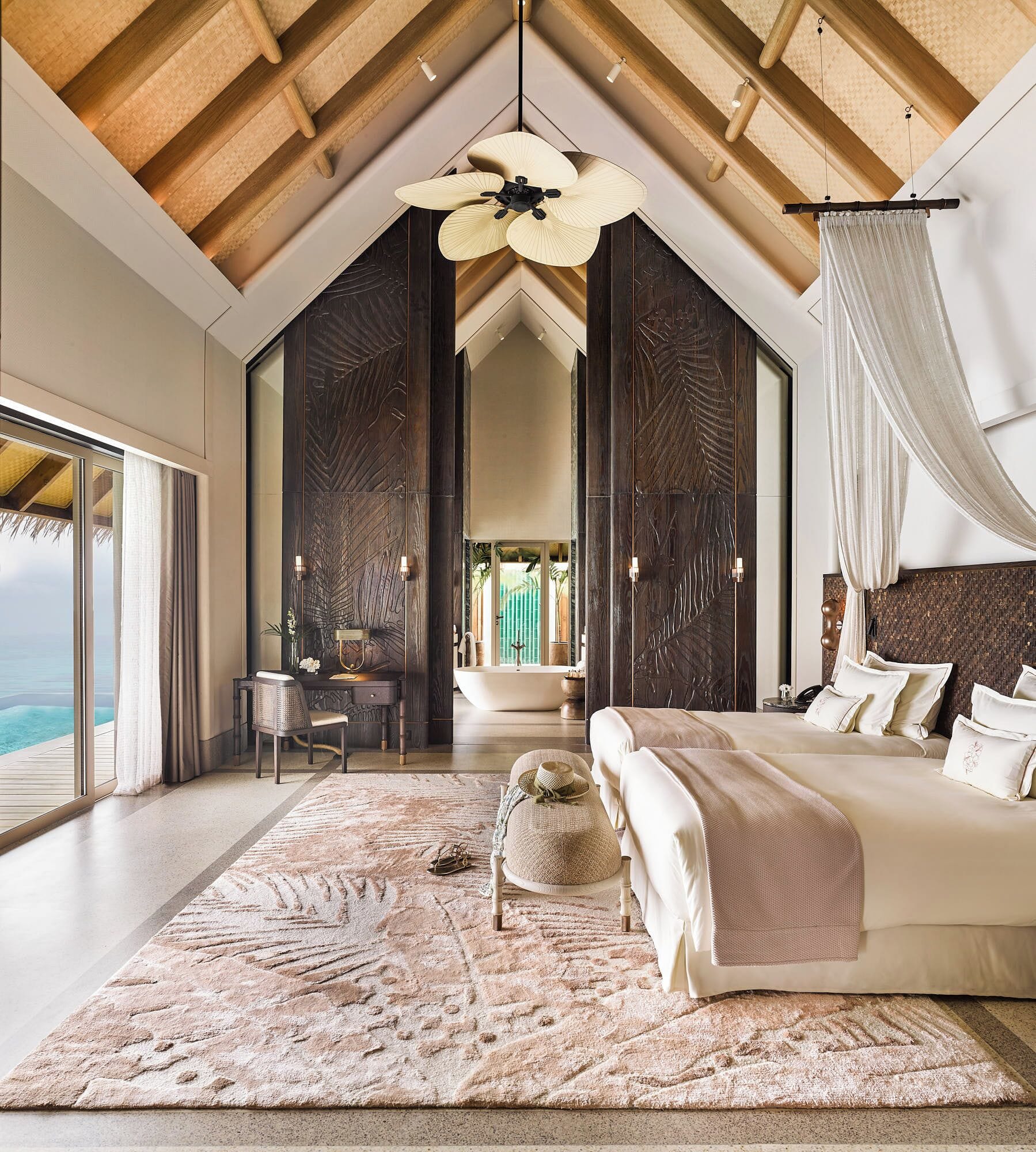 Design-led overwater villa bedroom opening to the sea at JOALI Maldives