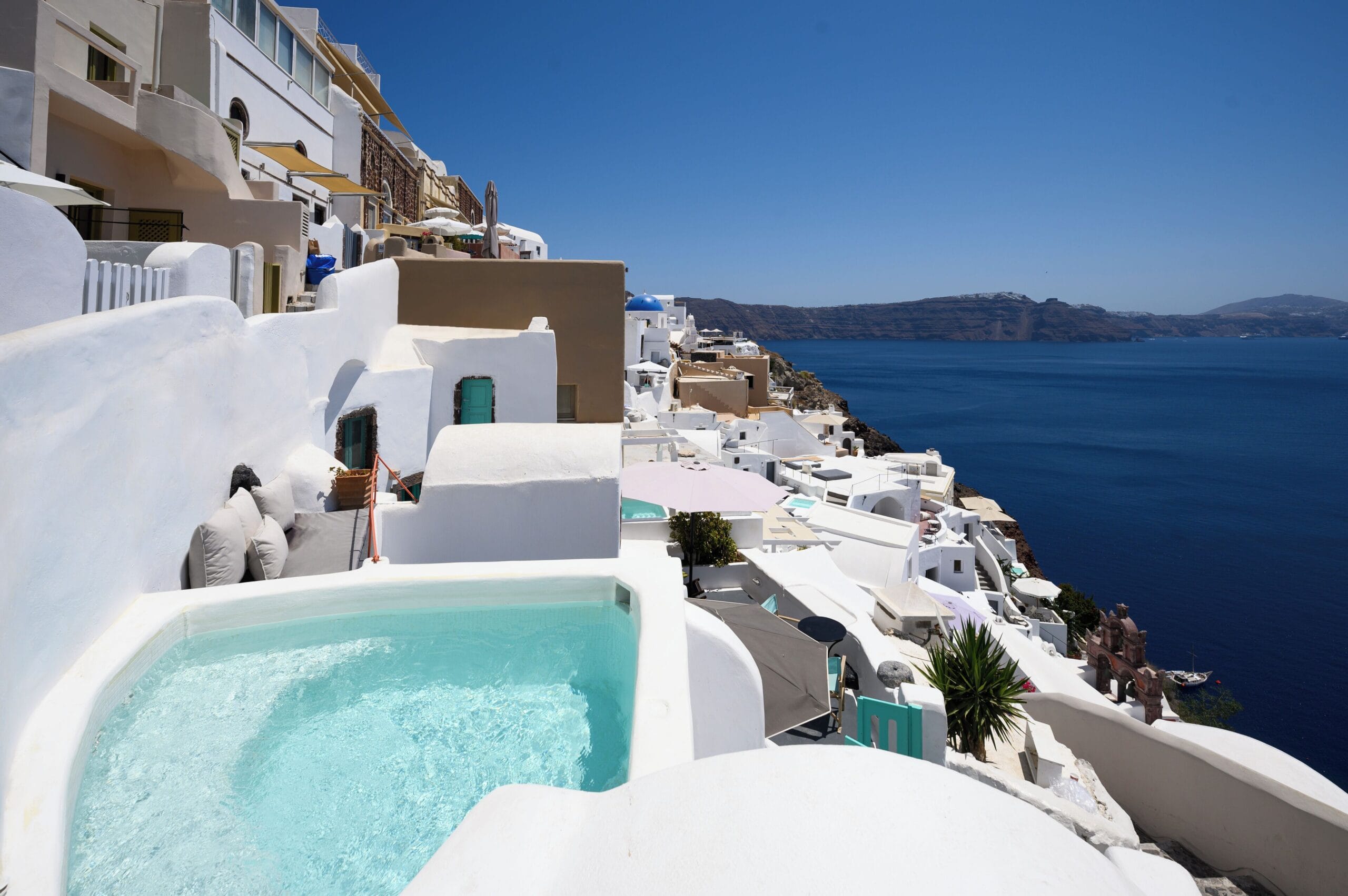 Whitewashed hotels stacked in tiers down the caldera cliff in Oia, Santorini, Greece